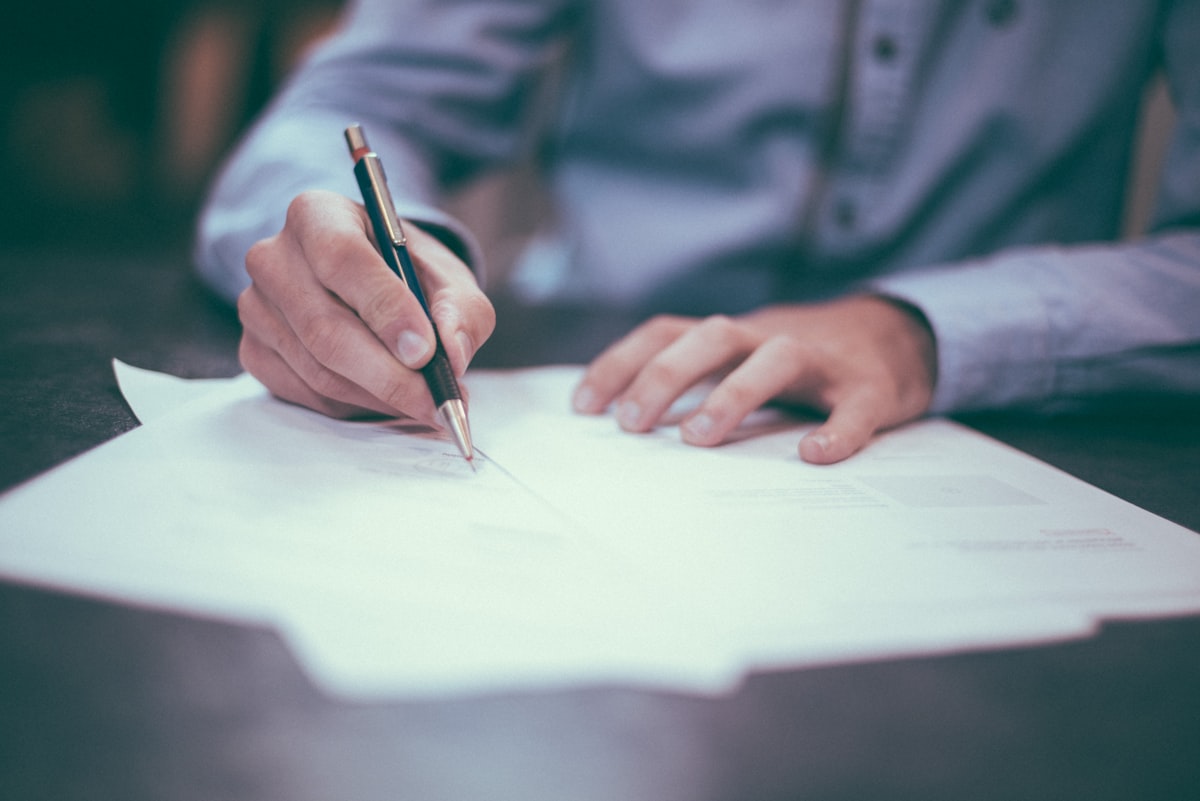 Man carefully counting and recording monthly budget figures at his desk, disciplined stewardship planning
